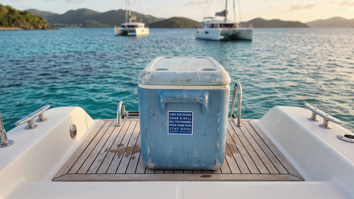 Cooler with a Bareboat Yacht Club motto sticker on the teak transom of a catamaran at anchor